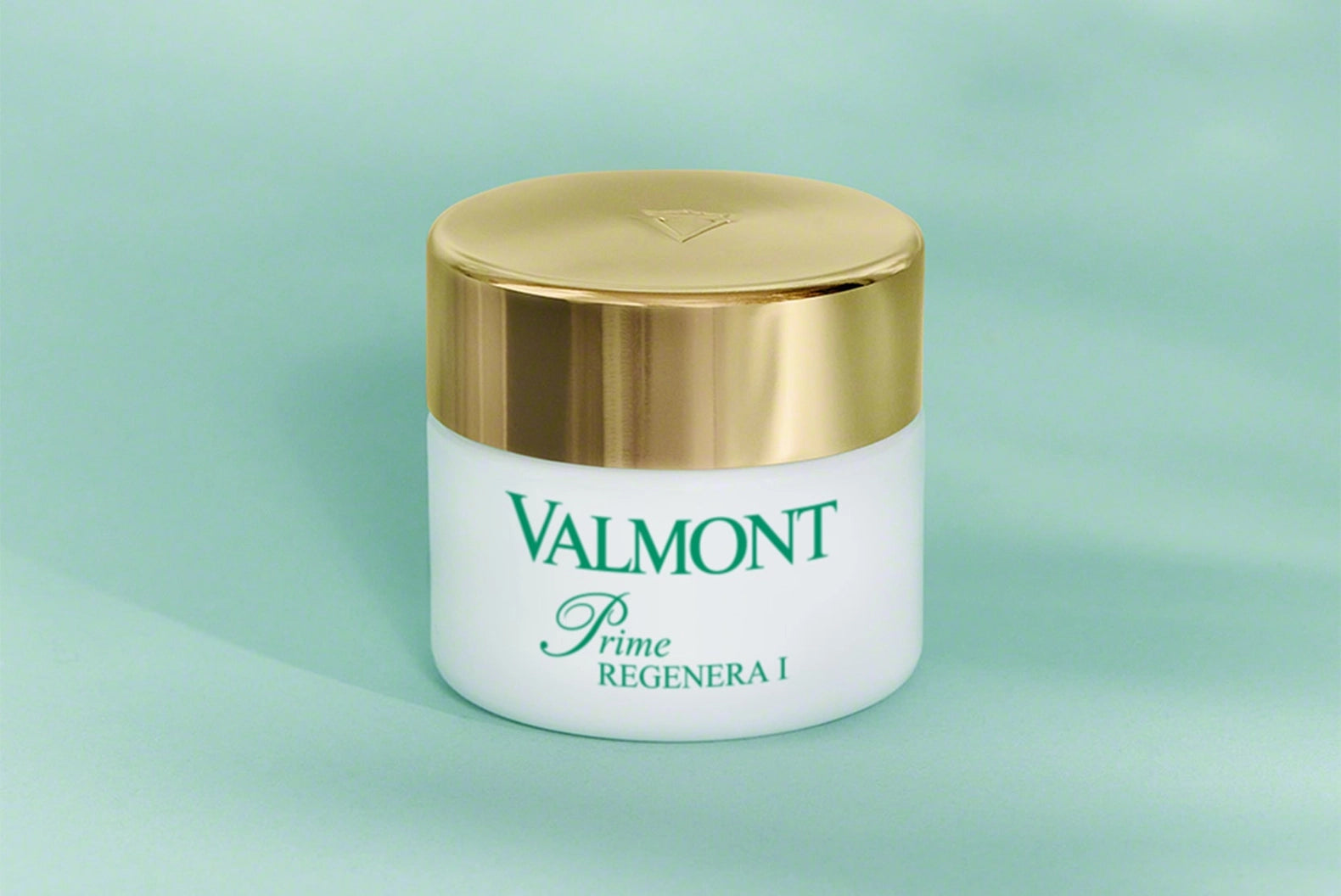 Valmont skincare jar with gold lid on a light green background