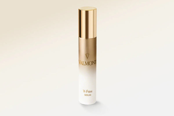 Skincare serum bottle with gold cap and white body on a light beige background