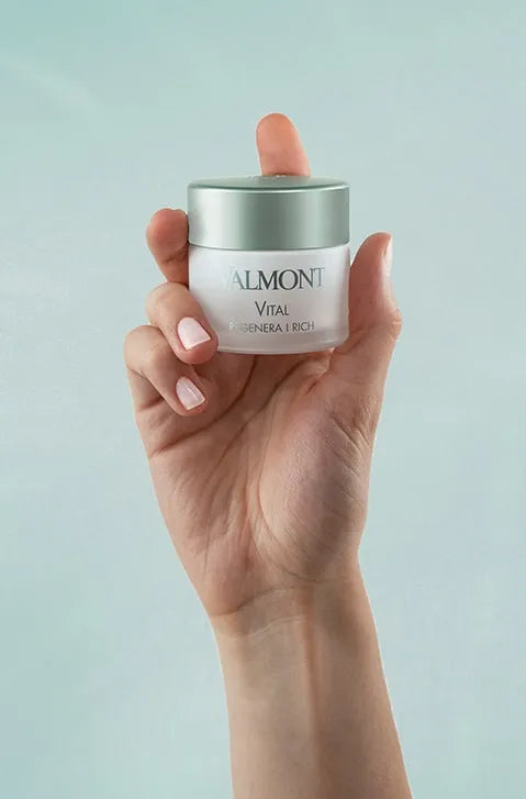 Hand holding a jar of Almonti skincare product against a light green background